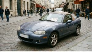 Mazda MX-5 NB bleu à vendre, stationnée dans une rue pavée en centre-ville