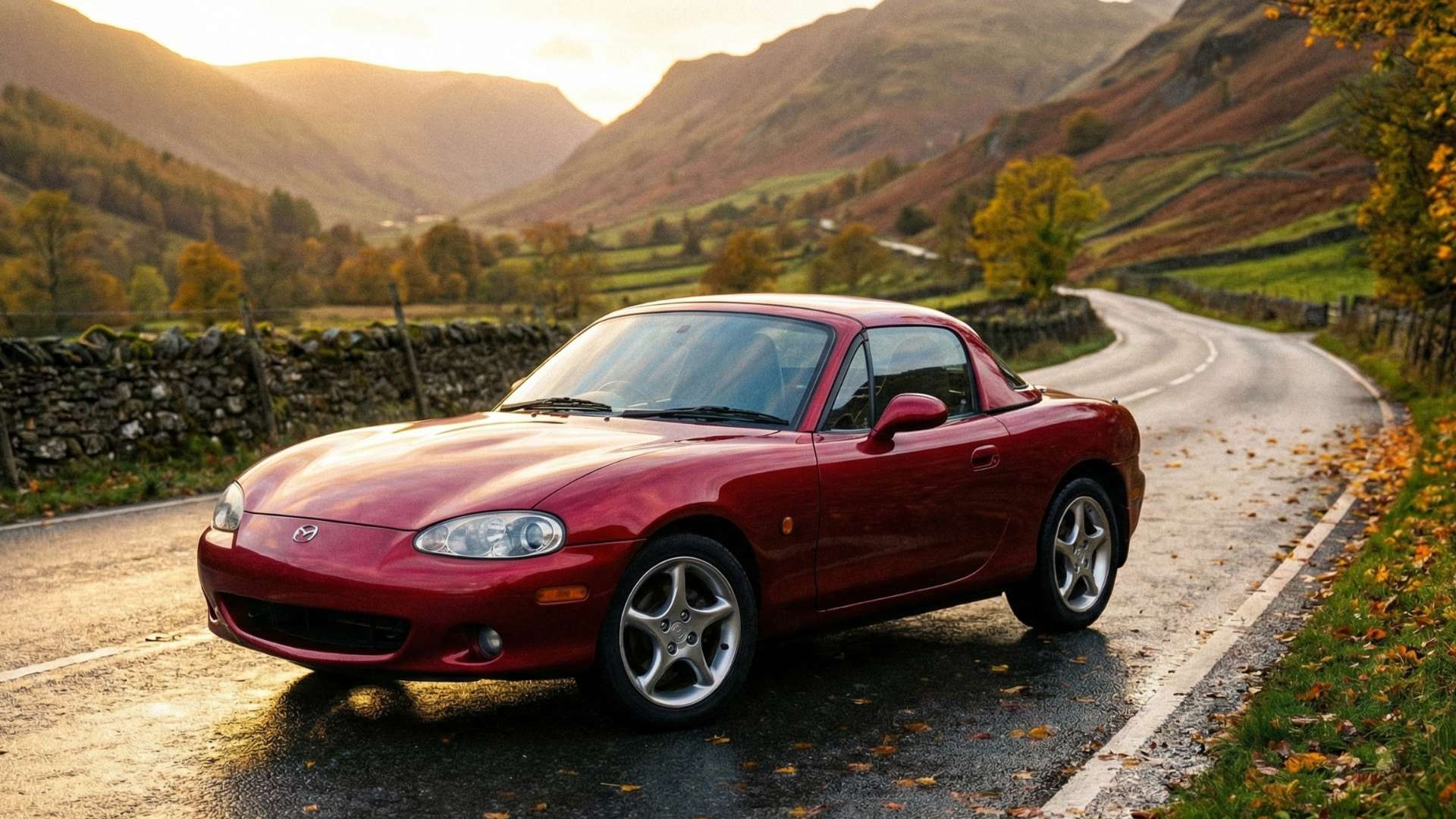 Mazda MX-5 NB rouge sur route de montagne au coucher du soleil