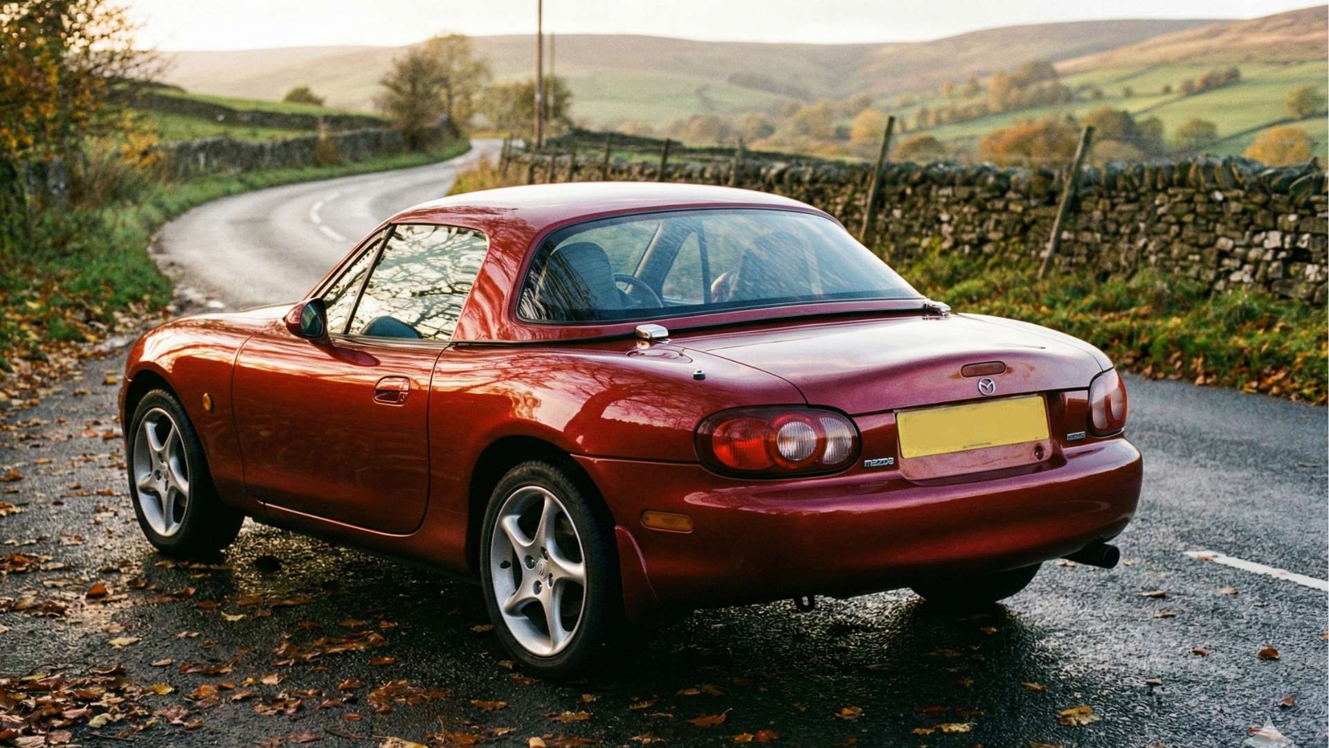 Mazda MX-5 NB rouge vue arrière sur une route de campagne en automne