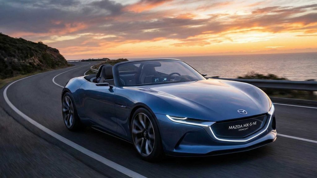 Mazda MX-5 NE conceptuelle, bleue sur une route de montagne sous un couché de soleil
