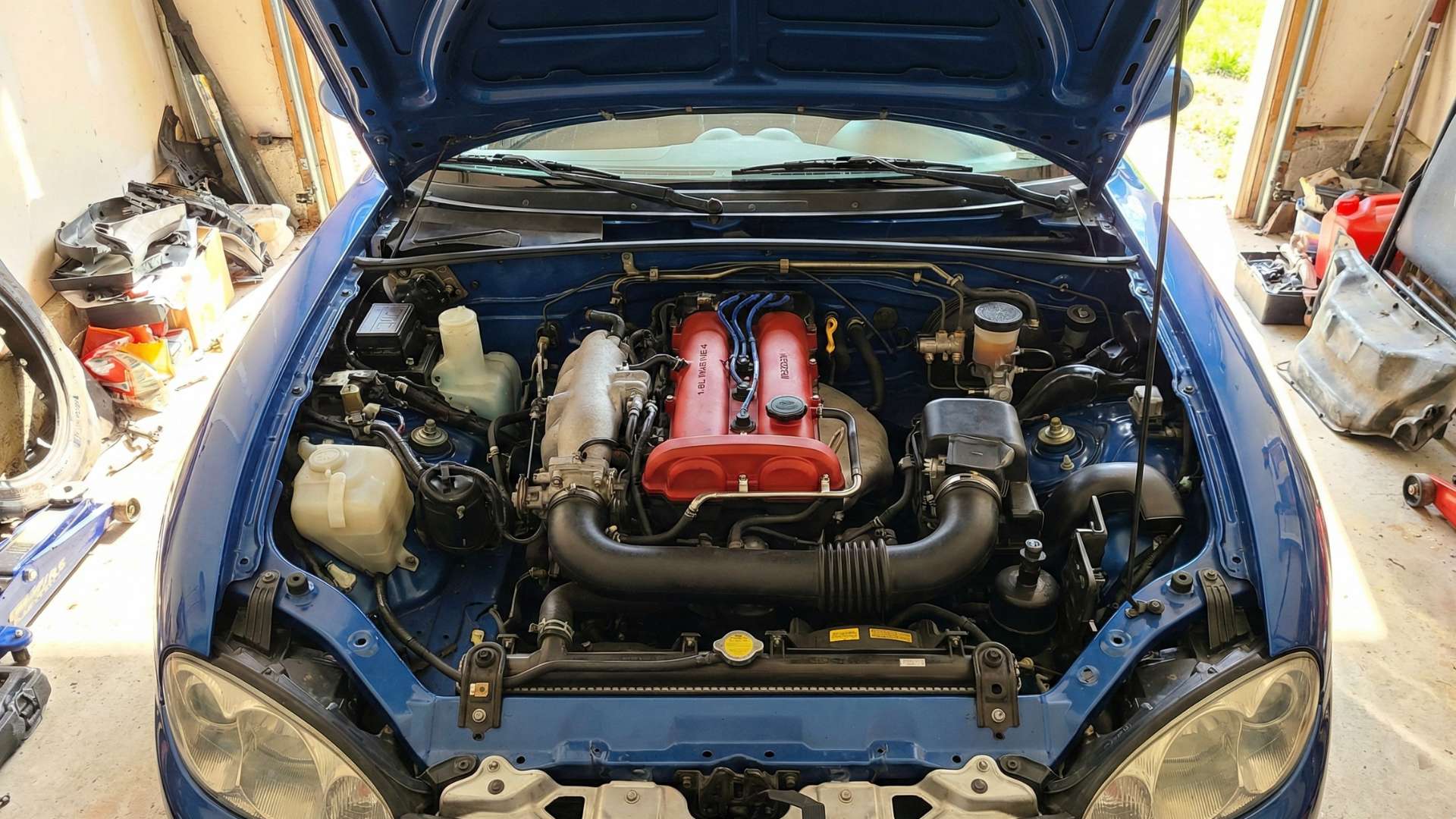 Vue rapprochée du compartiment moteur d'une Mazda MX-5 NBFL bleue avec le capot ouvert
