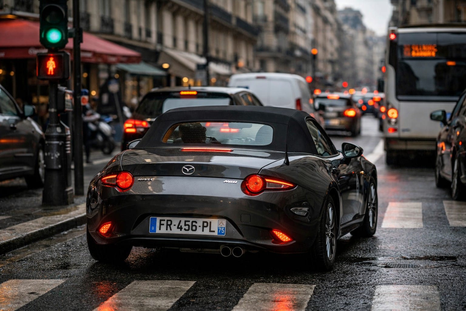 Mazda MX-5 grise en circulation urbaine sous la pluie, illustrant la consommation réelle en ville avec arrêts et redémarrages fréquents