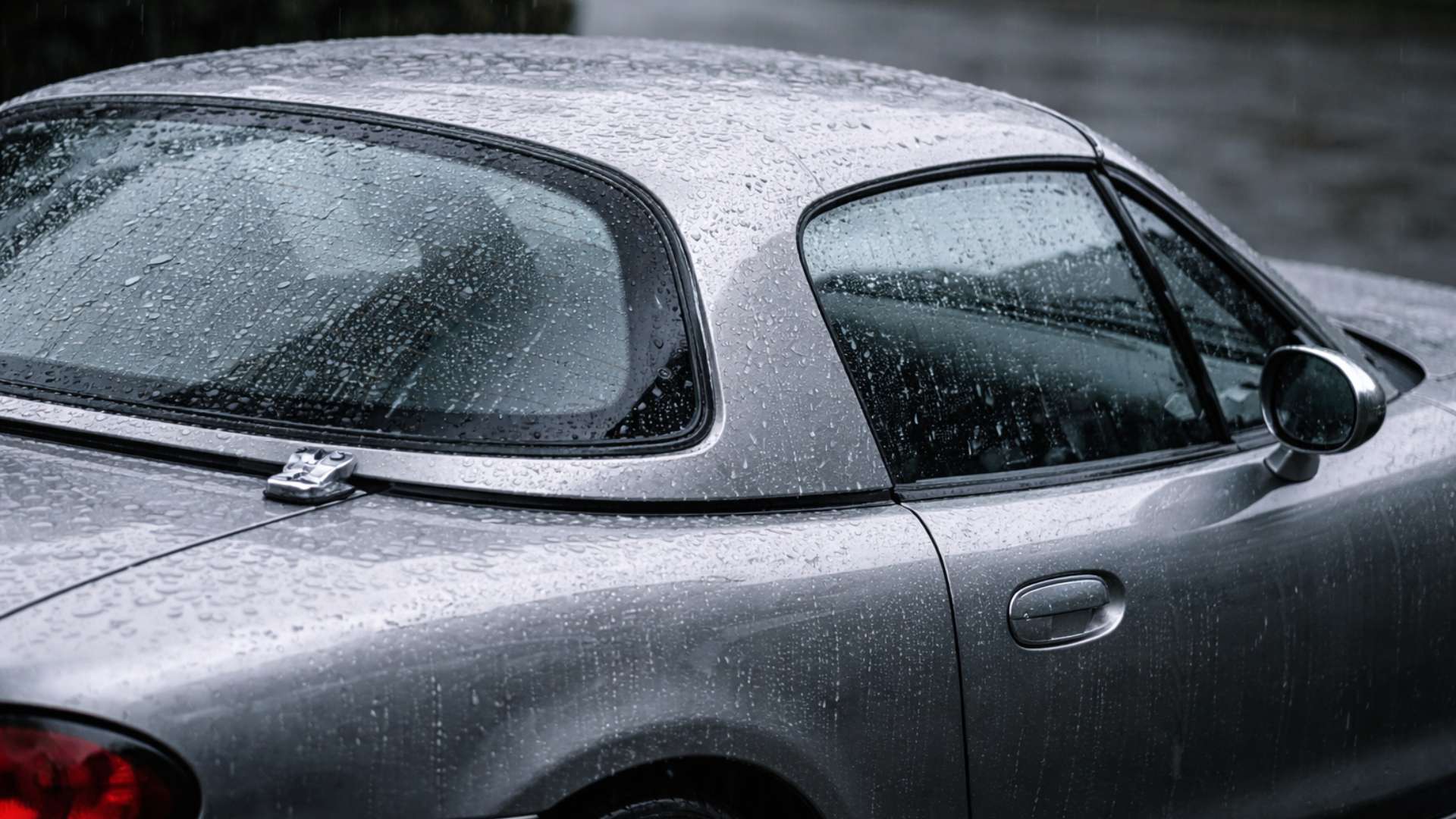 Hardtop Mazda MX-5 NBFL gris sous la pluie, gros plan sur les joints et l'étanchéité du toit rigide