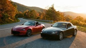 Mazda MX-5 ND rouge et Honda S2000 noire stationnées sur une route de montagne sinueuse pour un comparatif de roadsters japonais iconiques.