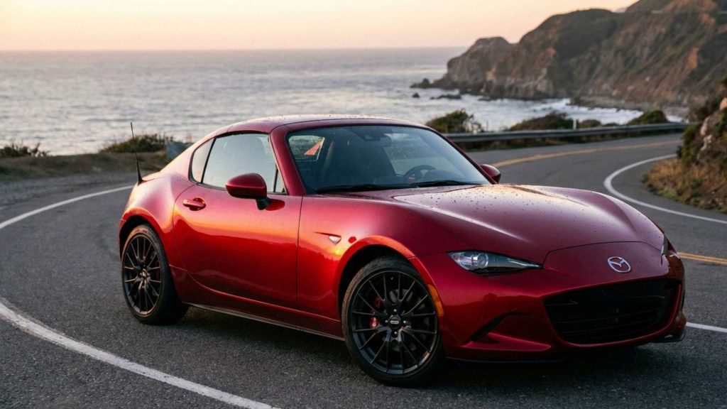Mazda MX-5 RF rouge stationnée sur une route côtière au coucher du soleil, avec l’océan et des falaises en arrière-plan.