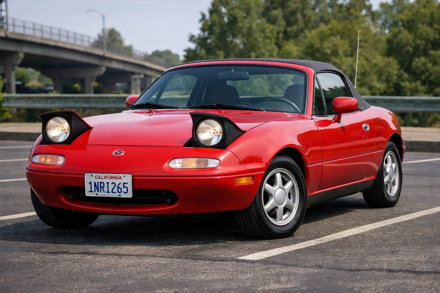 Red 1990 NA Miata roadster, front three-quarter view in daylight