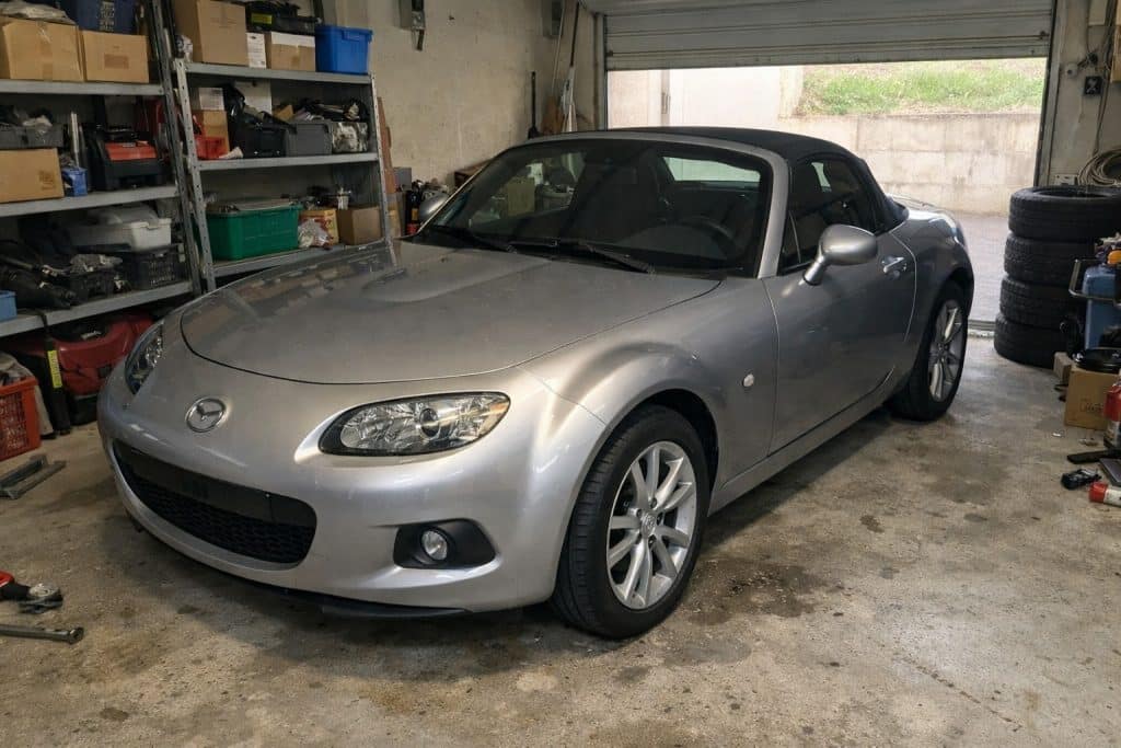 Photo réaliste d’une Mazda MX-5 NC grise garée dans un garage privé à Orléans, éclairage naturel et ambiance atelier