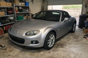 Photo réaliste d’une Mazda MX-5 NC grise garée dans un garage privé à Orléans, éclairage naturel et ambiance atelier