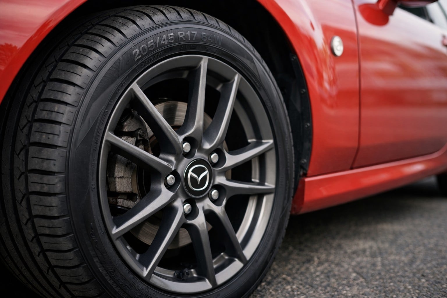 Gros plan d’un pneu 205/45 R17 monté sur une jante Mazda d’une Mazda MX-5 NC rouge, photo réaliste pour illustrer tailles homologuées et pression