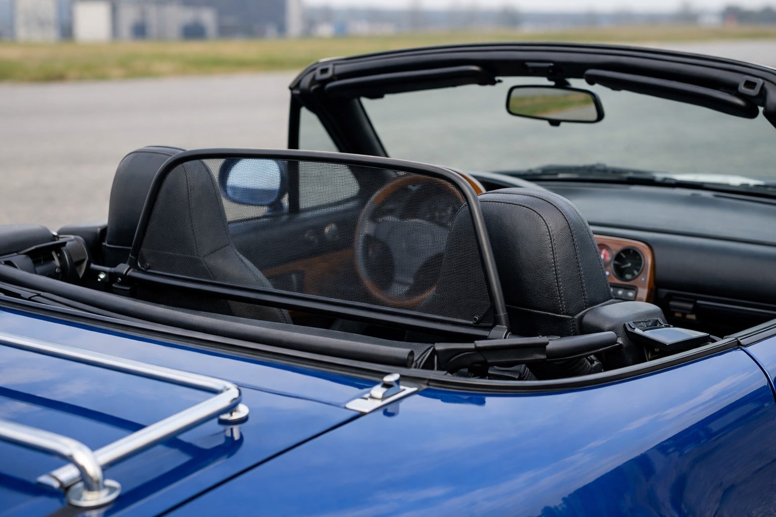 Windschott (déflecteur de vent) installé entre les sièges d’une Mazda MX-5 NA bleue décapotée, vue intérieure premium
