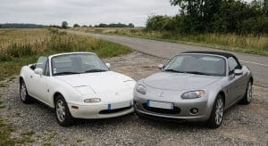 Comparaison de deux générations de Mazda MX-5 : une NA blanche (première génération) et une NC argentée (troisième génération) garées côte à côte en France.