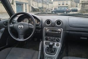 Intérieur d’une Mazda MX-5 NBFL grise à Vendôme, photographié en lumière naturelle, avec tableau de bord et sièges visibles