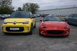 Mazda MX-5 ND rouge garée à côté d’une Renault 5 2026 jaune sur un parking, vue de face, photo réaliste en lumière naturelle sous ciel couvert