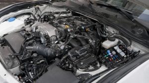 Vue du compartiment moteur d’une Mazda MX-5 ND avec focus sur les capteurs, le faisceau électrique, les connecteurs électroniques et la boîte à fusibles ouverte lors d’un contrôle mécanique.