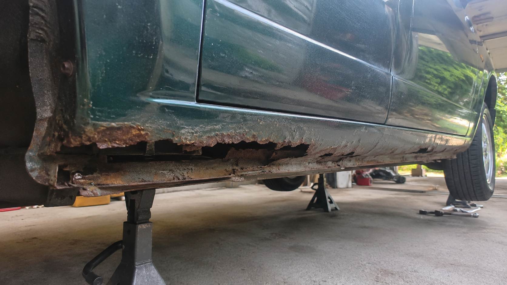 Bas de caisse perfore par la rouille sur une Mazda MX-5 NB verte levee sur chandelles