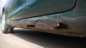 Blackson écaillé et rouille perforante sur le bas de caisse d'une Mazda MX-5 verte