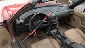 Canne antivol rouge et noire verrouillée sur le volant d'une Mazda MX-5 NA rouge à intérieur cuir beige