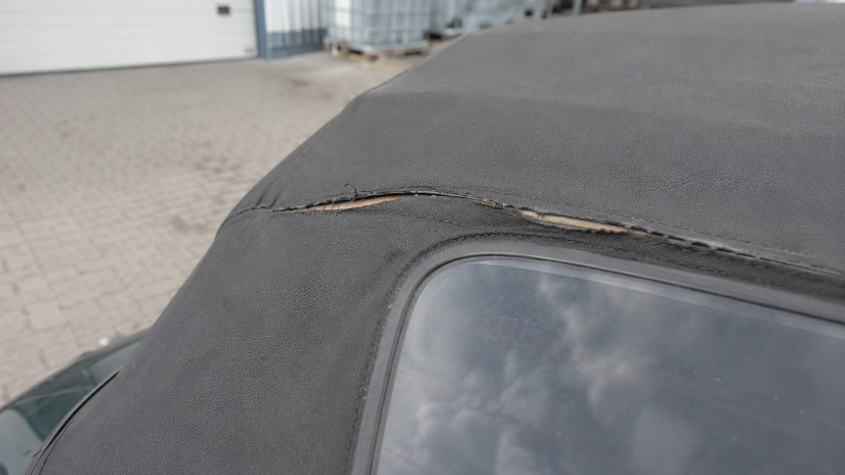 Capote noire de Mazda MX-5 déchirée le long de la couture au-dessus de la lunette arrière