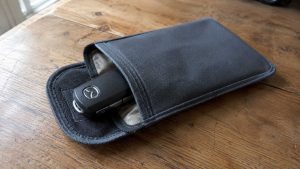 Clé Mazda rangée dans une pochette Faraday anti-RFID posée sur une table en bois