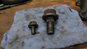 Comparaison de deux boulons de poulie de vilebrequin de Mazda MX-5 posés sur un chiffon d'atelier bleu