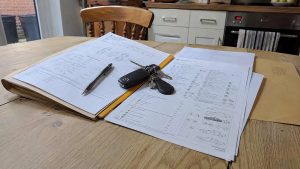 Carnet d'entretien, rapports d'inspection et clé Mazda posés sur une table en bois avant l'achat d'une MX-5