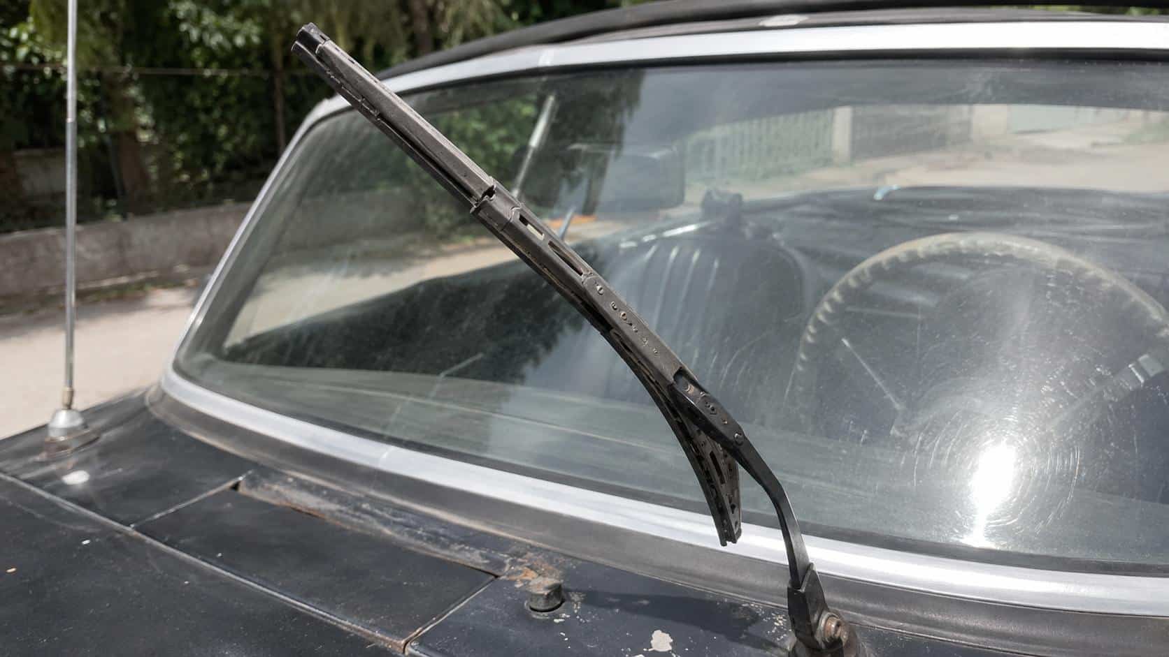 Balai d'essuie-glace usé relevé devant le pare-brise d'une voiture ancienne noire