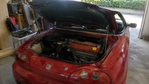 MG TF rouge avec capot moteur ouvert révélant son moteur central quatre cylindres