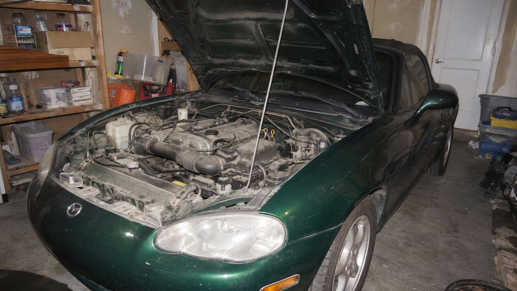 Compartiment moteur d'une Mazda MX-5 NB verte capot ouvert dans un garage