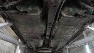 Planchers avant symétriques, rail central et conduites de frein sous une Mazda MX-5 verte sur pont