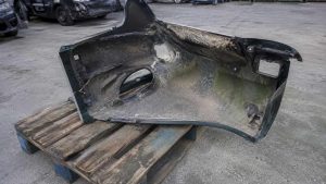 Quart arrière vert de Mazda MX-5 vu face intérieure avec découpe de feu, posé sur une palette en casse auto
