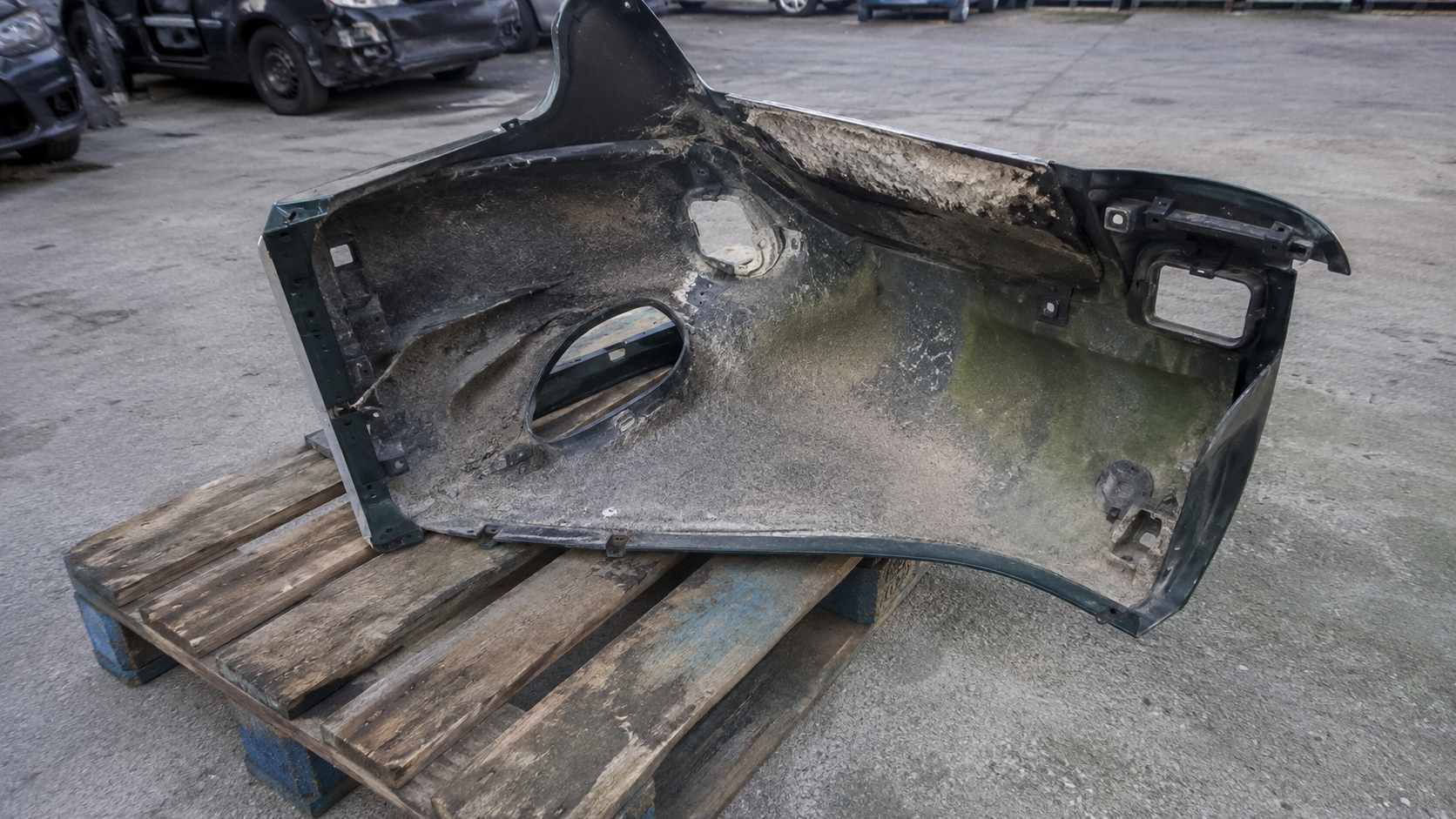 Quart arrière vert de Mazda MX-5 vu face intérieure avec découpe de feu, posé sur une palette en casse auto